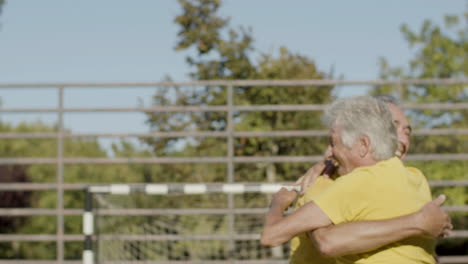 happy senior sportsmen hugging and smiling after scoring goal