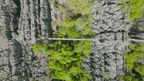 Aerial-topshot-of-tourist-walking-on-the-rope-bridge-between-rocks-in-Tsingy---Madagascar