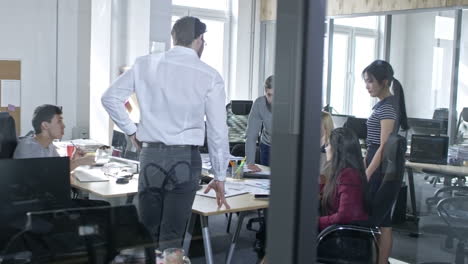 multi ethnic group of business professionals discussing documents in meeting room with glass walls