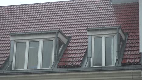 rain falling on urban rooftop with two windows in slow motion