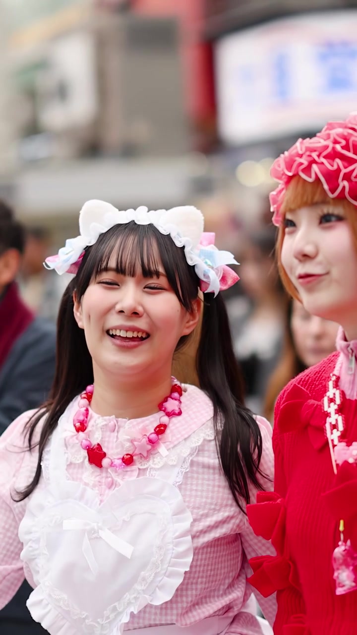 Adolescenti sorridenti con vivace stile street giapponese camminano attraverso una città affollata ad Harajuku, Tokyo.