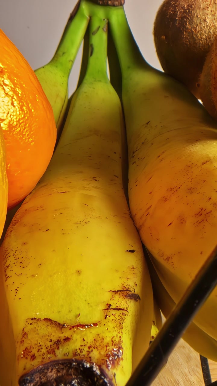 Plátanos y naranjas maduros dispuestos juntos en una cesta de frutas, iluminados por luz cálida