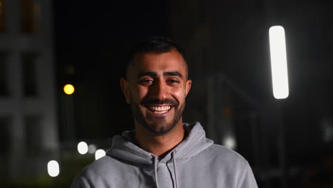 hombre sonriendo por la noche en la ciudad
