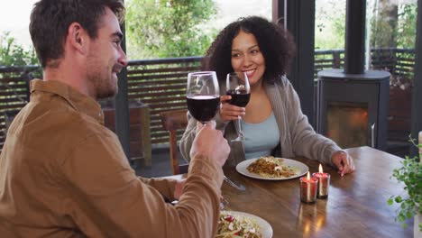 Paar-Gemischter-Rassen-Prostet-Zu-Und-Trinkt-Wein,-Während-Es-In-Einem-Restaurant-Zu-Mittag-Isst