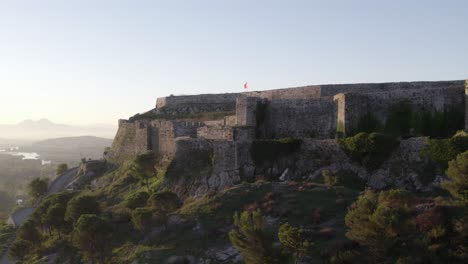 Flying-forwards-to-Schloss-Shkodra-with-albanian-flag-waving,-aerial