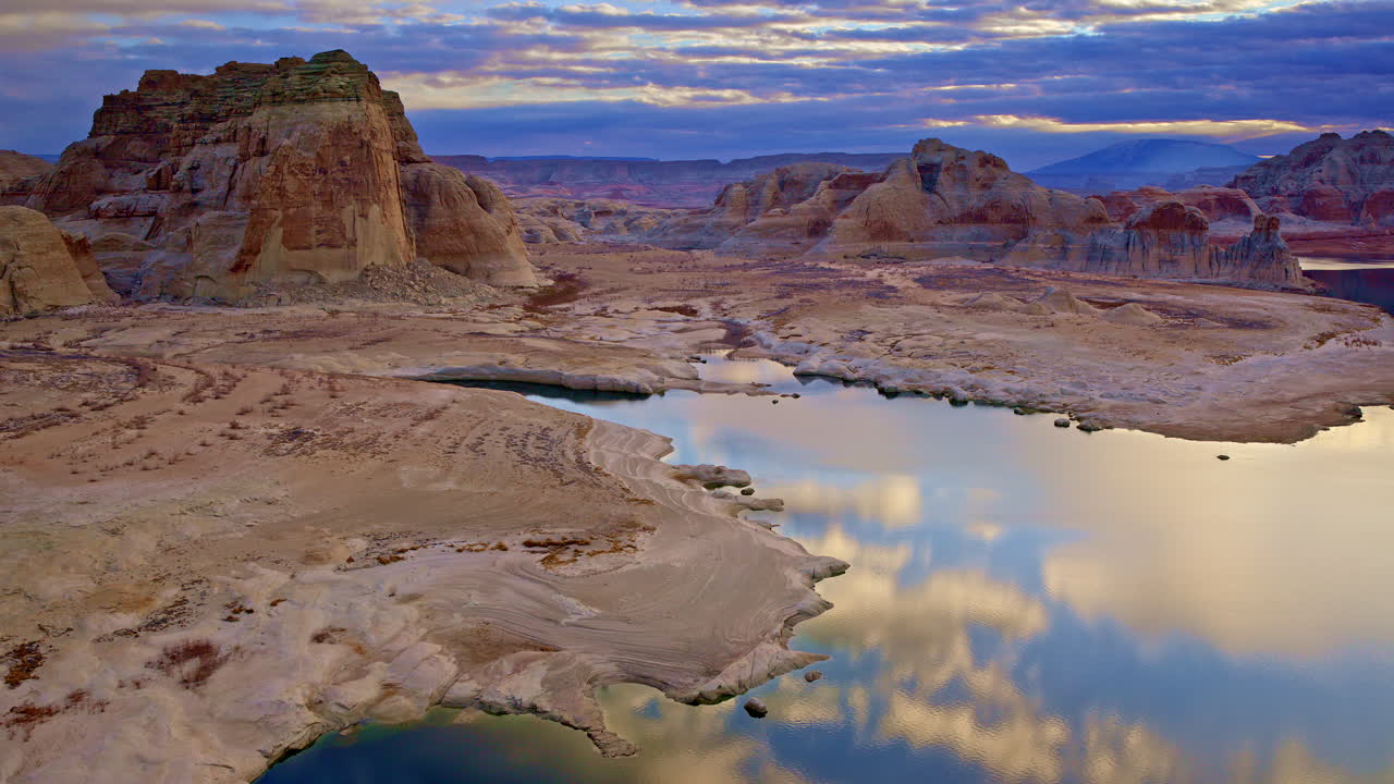 A dramatic drone view soaring over the sculpted red rock formations and arid desert plains near Lake Powell.