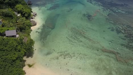 PADANG-PADANG-BEACH,-drone-flying-over-the-beach-towards-emerald-water-sea,-Bali-Indonesian,-crystal-clear-water