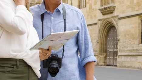 Mid-section-of-Tourist-Couple-Reading-Map-on-Street