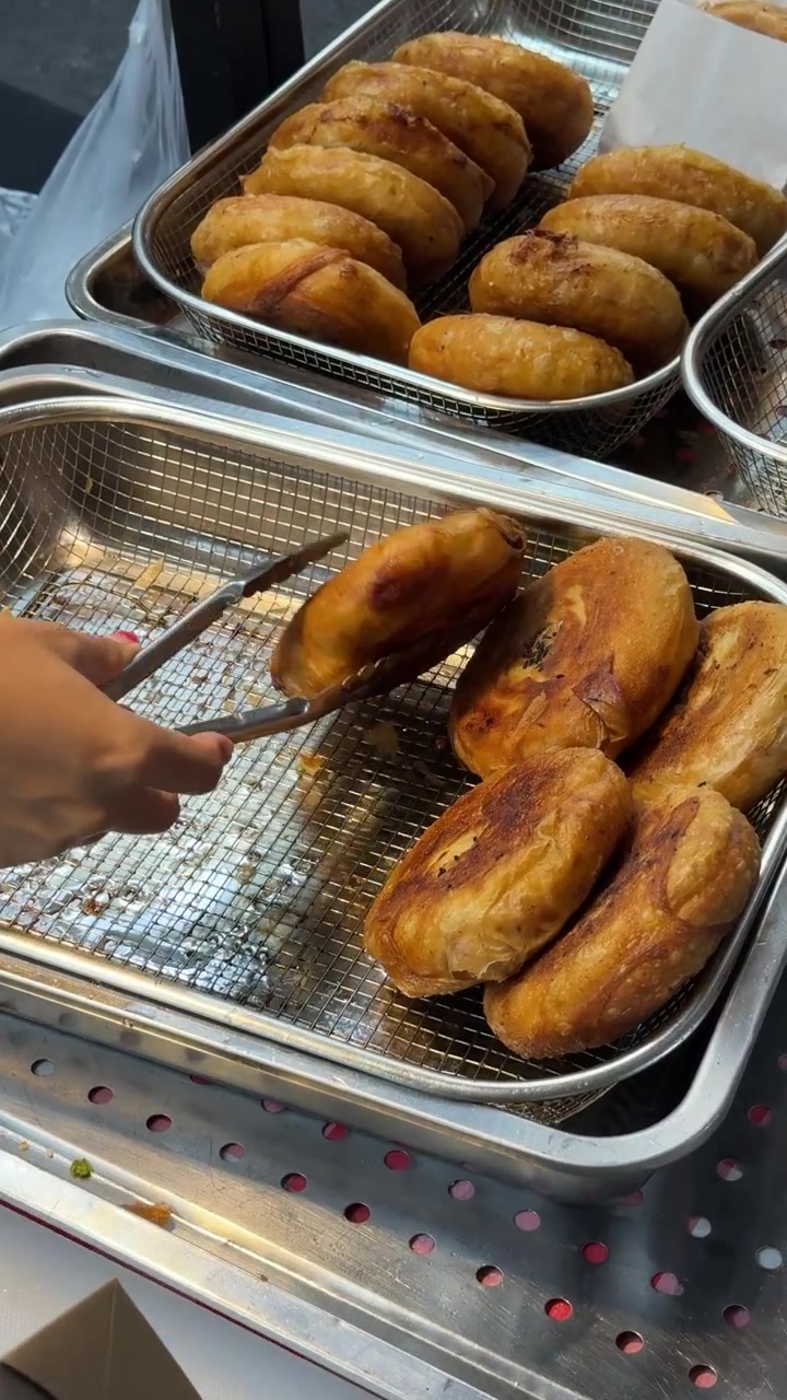 Venditore di street food che sistema frittelle con le pinze