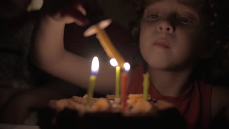 Vista-En-Cámara-Lenta-De-Una-Niña-Pequeña-Encendiendo-Las-Velas-Del-Pastel-De-Cumpleaños-En-La-Oscuridad