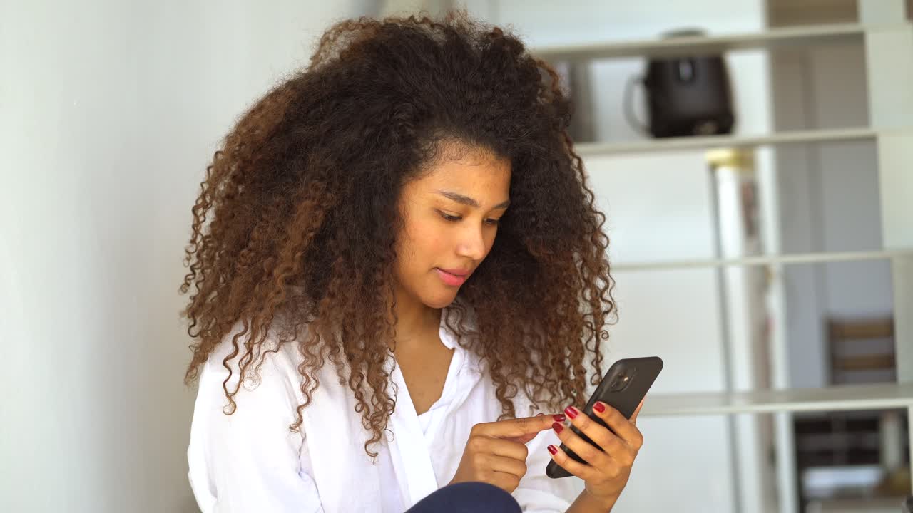 Ethnic woman browsing smartphone at home