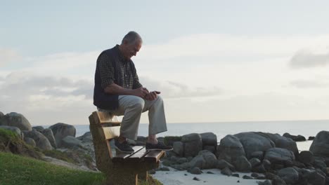 senior man using his mobile phone while sitting on a bench