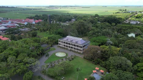 Luxury-house-surrounded-by-tropical-plants,-aerial-push-in