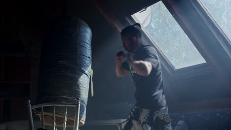 man training with punching bag in attic