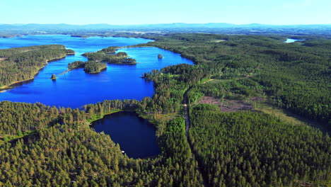 lush green island landscape surrounded by deep blue sea in vansbro municipality, dalarna county, sweden - aerial shot