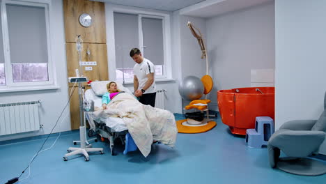 expecting couple in the modern comfortable hospital ward. pregnant lady lies in bed and her husband comforts her during contractions.