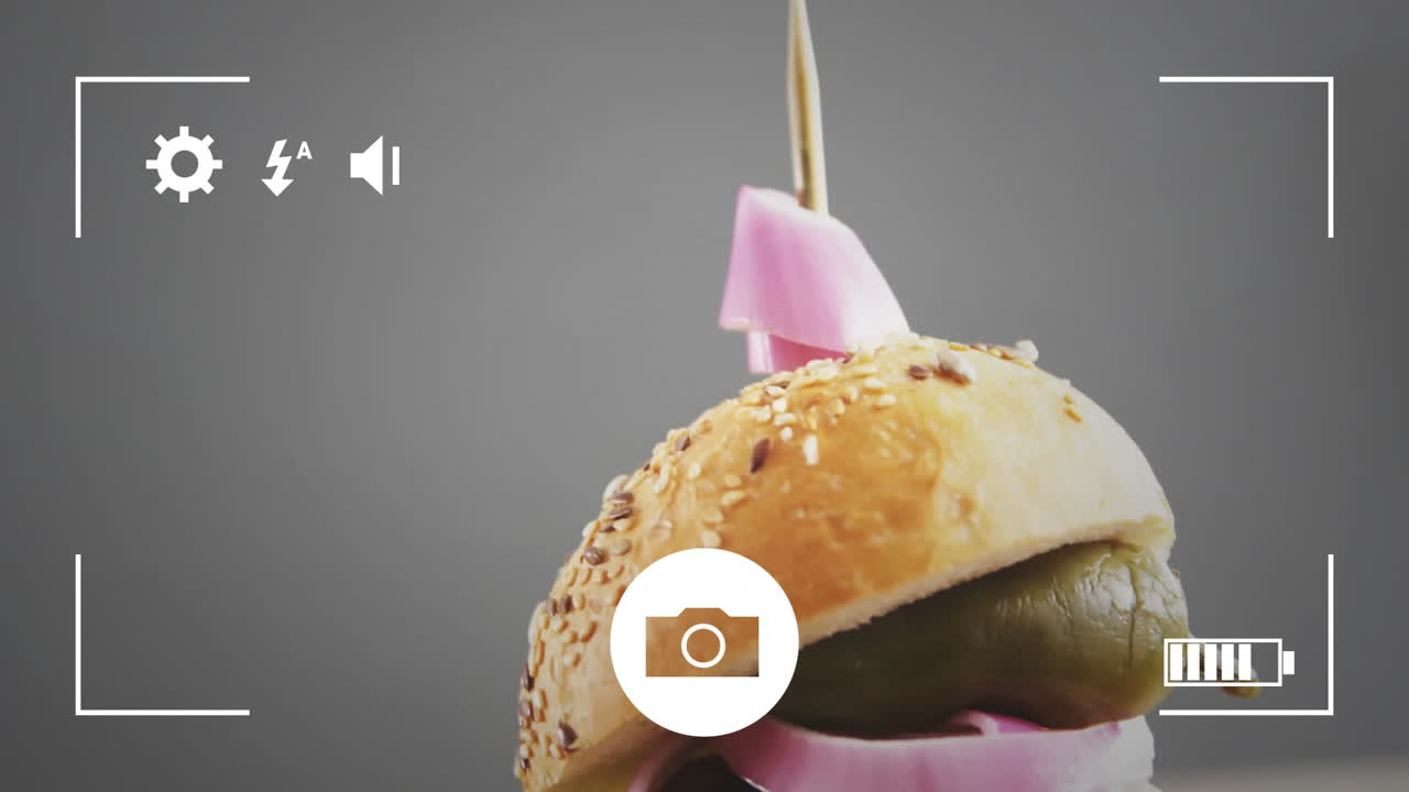 Camera interface animation over close-up of burger with toothpick and pink flag