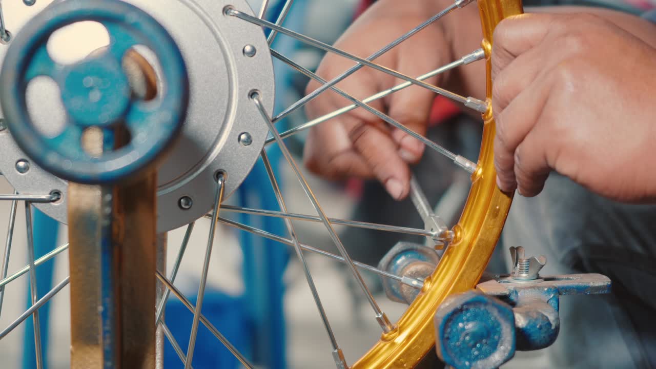 técnico hombre trabajando rueda de motocicleta tiene rayos tejer en herramienta mecánica nueva rueda de acero