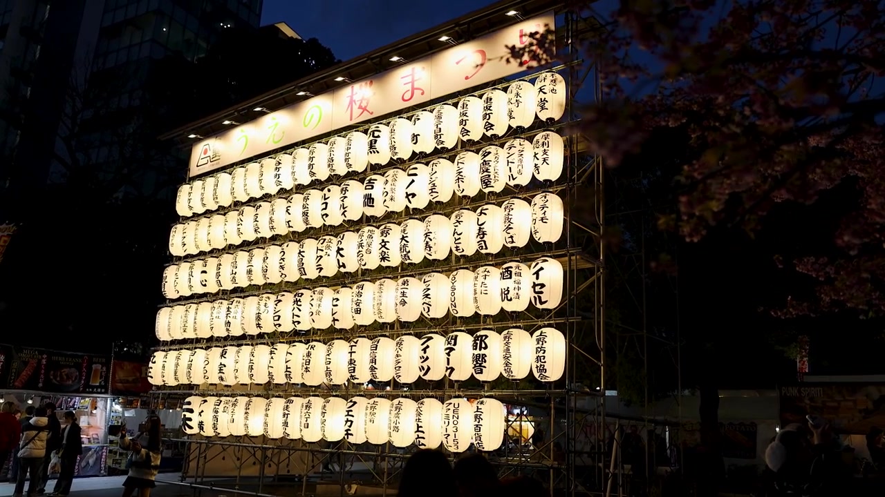 Rækker af glødende papirlanterner oplyser en nattefestscene i Tokyos Ueno Park.