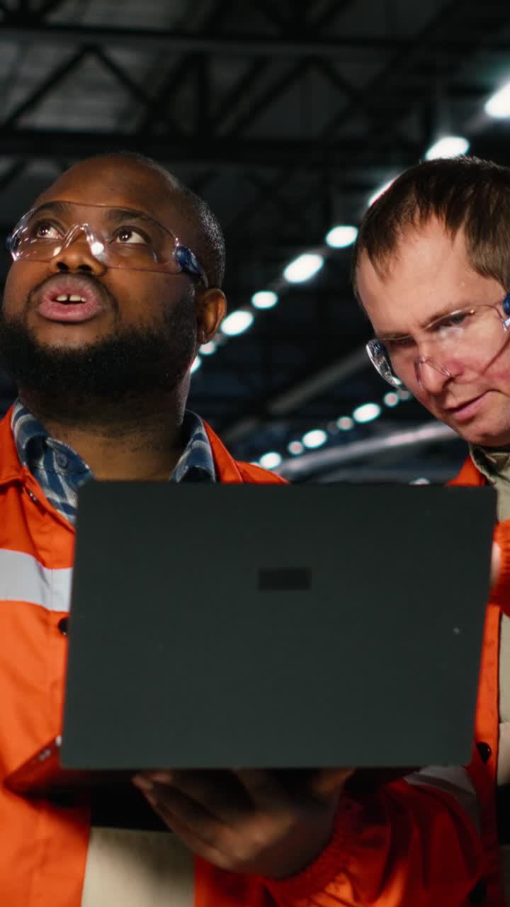 Vertical Video Diverse operators use laptop to coordinate production activity on factory floor