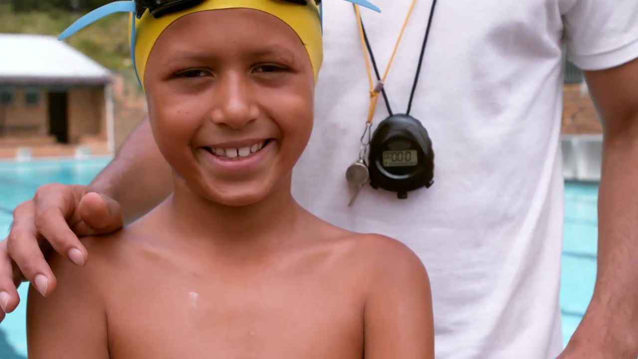 수영장 근처 의 코치 와 함께 서 있는 미소 짓는 소년