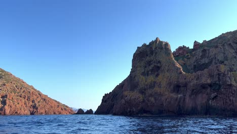 Eroded-rock-formations-of-Scandola-nature-reserve-seen-from-tour-boat-in-summer-season,-Corsica-island-in-France