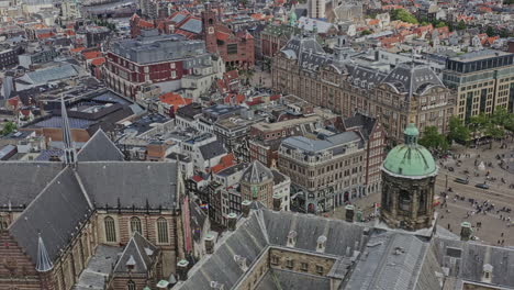 amsterdam netherlands aerial v14 drone fly above royal palace, birds eye view overlooking at busy dam square with national monument, with locals and tourists visiting the site - august 2021