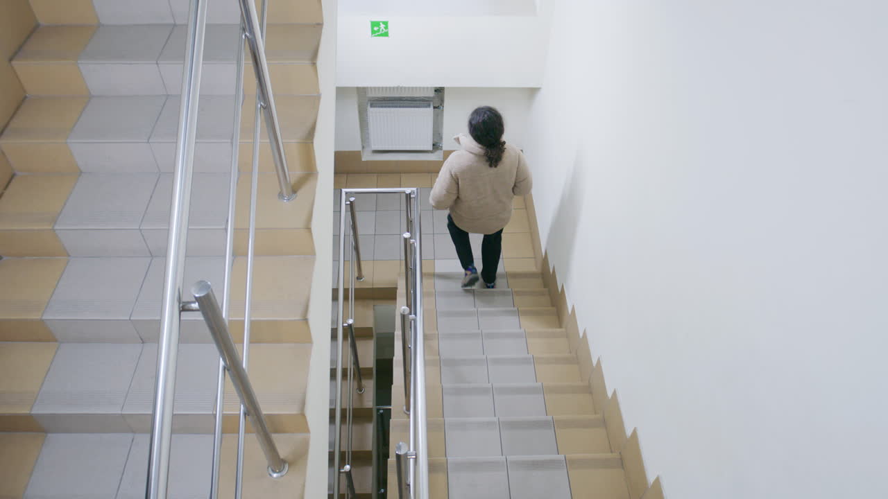 People walking down a staircase and an empty stairwell in a building