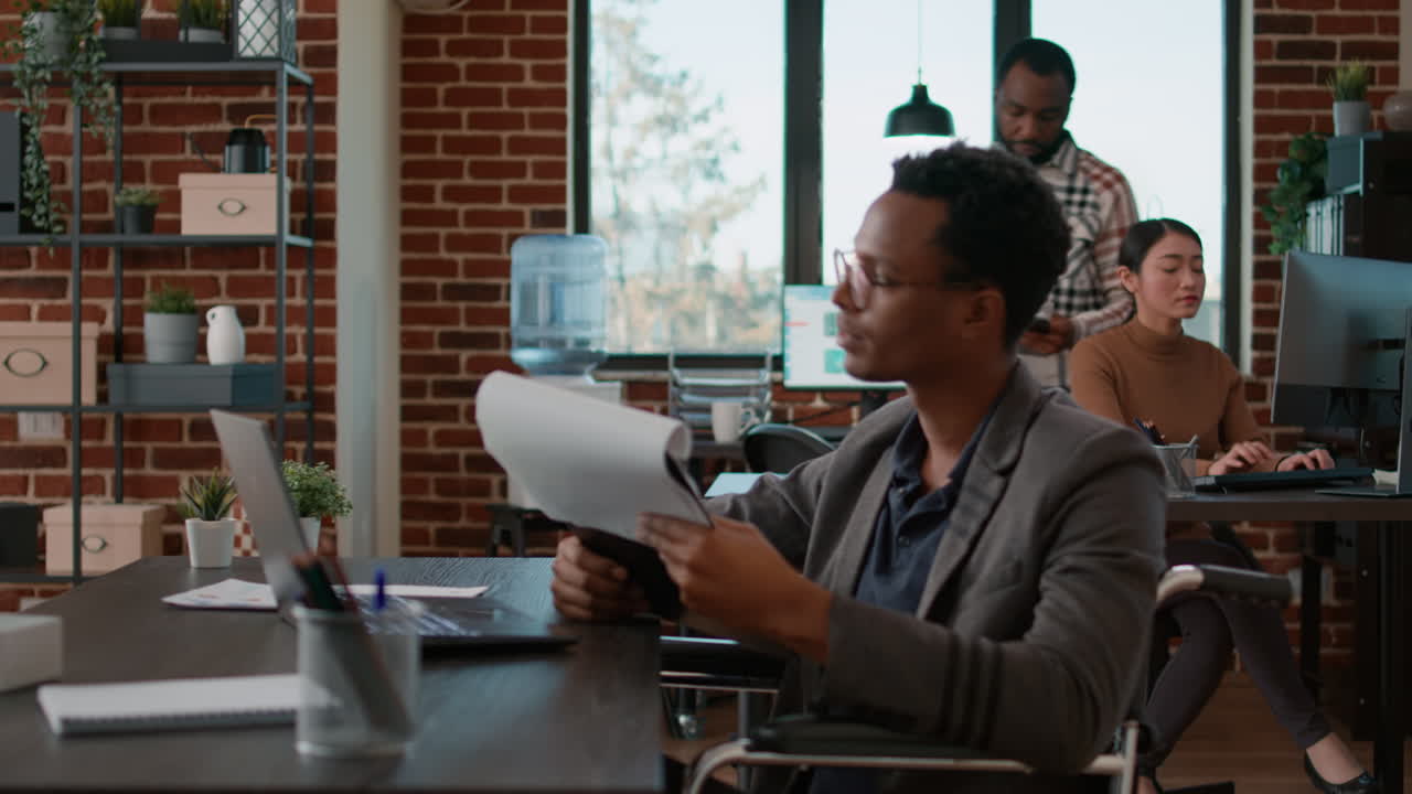 Man in wheelchair and woman with crutches collaborating on project