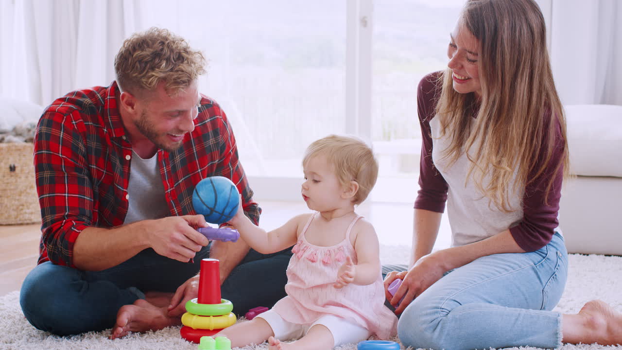 어린 부부 가 바닥 에 앉아 어린 딸 과 놀고 있다