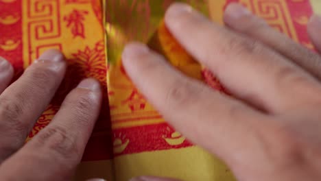hands folding traditional chinese joss paper for rituals
