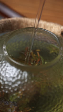 pouring water into a glass teapot