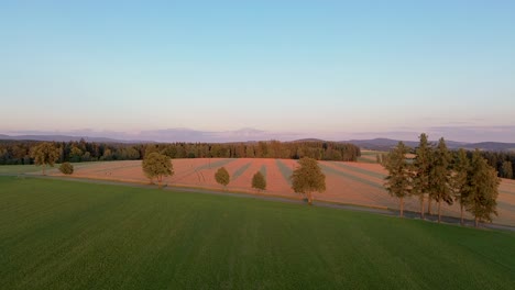 drone view timelapse in which the camera rises above the field during sunset