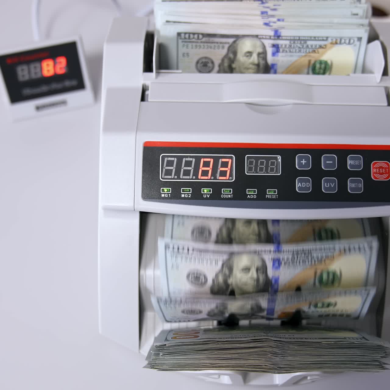 Impiegato che conta a mano i dollari con una macchina contabanote elettronica in un ufficio bancario o in un cambiavalute.