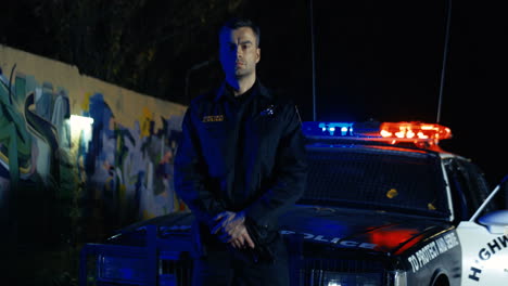 portrait shot of good looking brave policeman in uniform looking with serious face at camera on dark street