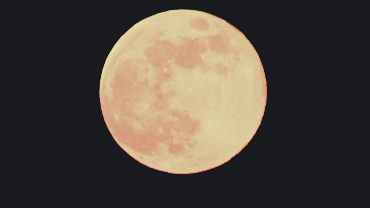 Close up of a bright full moon against a black night sky. Detailed surface texture is visible