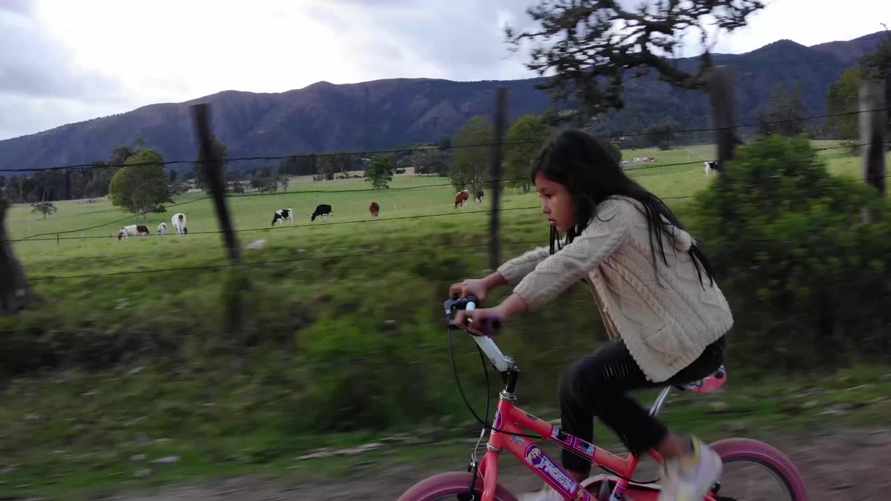 Filmopptak av en ung jente som sykler ned en landevei i Colombia