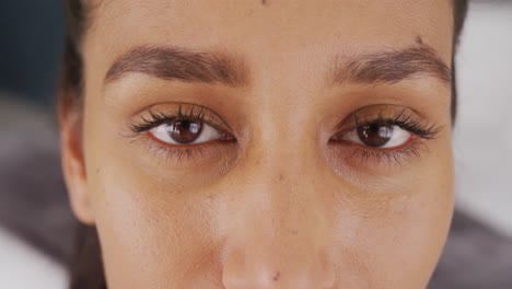 Video-close-up-portrait-of-eyes-of-happy-biracial-woman-smiling-to-camera-at-home