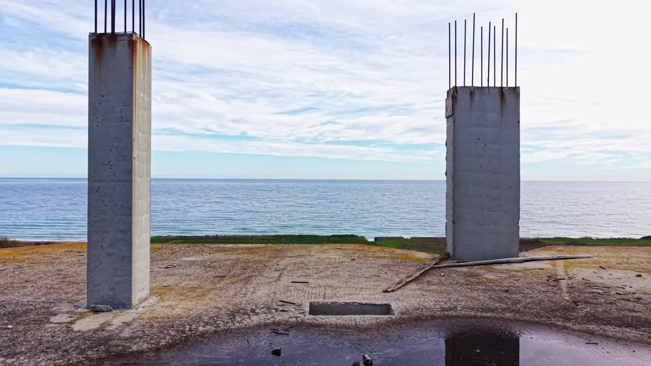 Urban ruins stand tall against a backdrop of the tranquil sea under a cloudy sky in this unique coastal construction site