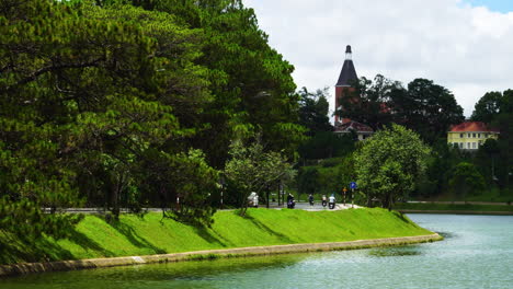 Vista-Estática-De-La-Exuberante-Orilla-Lateral-Del-Lago-Da-Lat-Con-La-Calle-Cruzada-Por