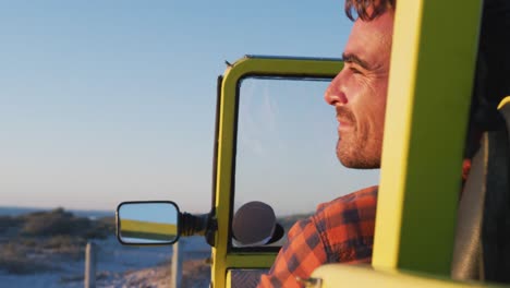 hombre caucásico feliz sentado en un buggy de playa junto al mar