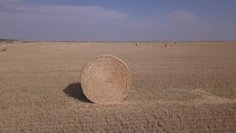 aerial orbits golden hay bale in agricultural field