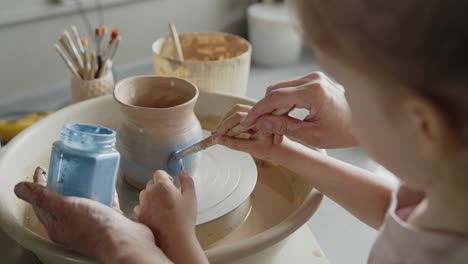 grandmother teaches her granddaughter working on a pottery rotating wheel