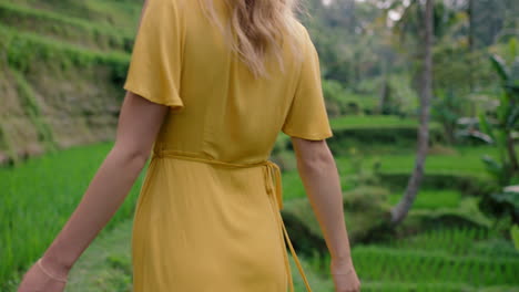 happy woman walking in rice paddy wearing yellow dress enjoying vacation exploring exotic cultural landscape travel through bali indonesia