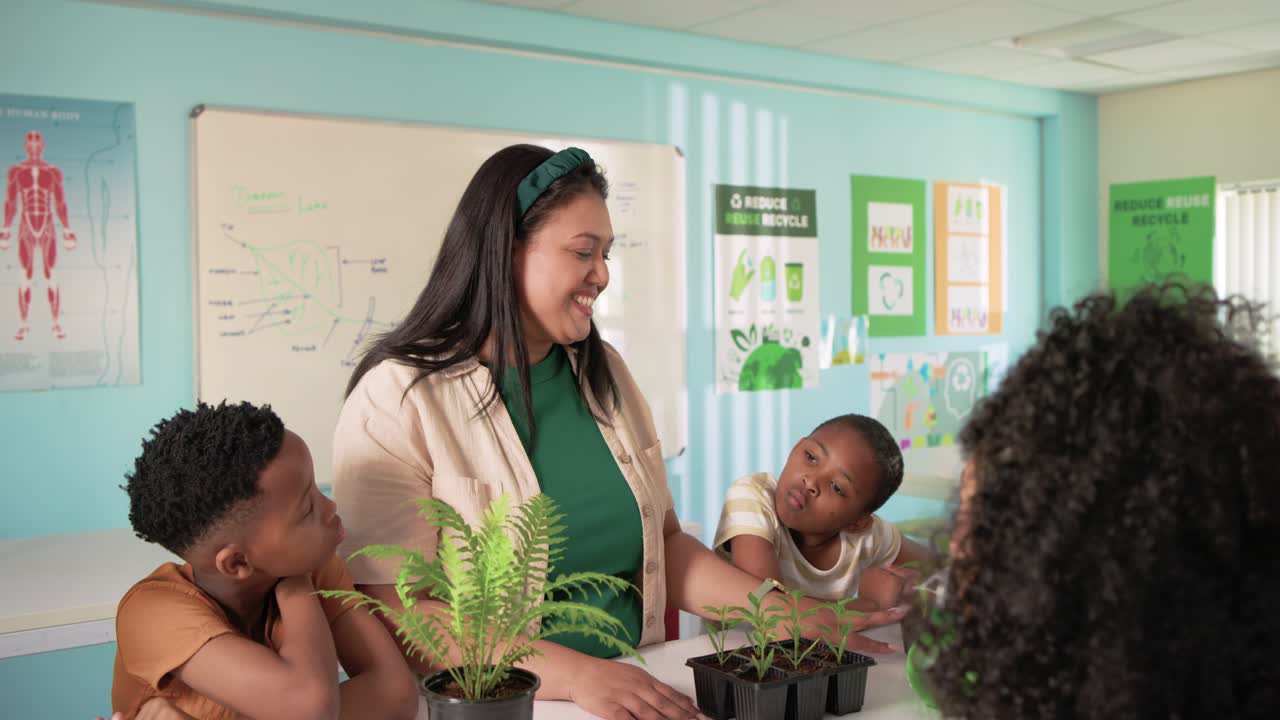 Teacher with five school-age kids teaching plant care at table redirecting child from spray bottle