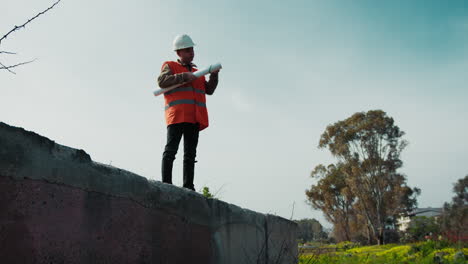 architect up on a wall at the outdoor construction site looking at the project
