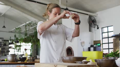 caucasian female chef adding an egg into a bowl