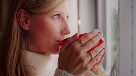 hermosa joven con ojos azules disfrutando de un café en la ventana, primer plano