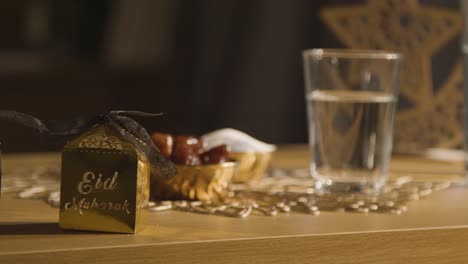 bowl of dates with glass of water and gift boxes on table in muslim home celebrating eid 2