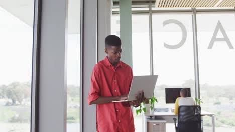 african american creative businessman standing with laptop in modern interiors